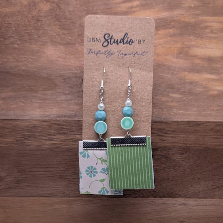 Earrings with white background blue flowered square front and green white stripe back with a few green/blue beads. Front and back is shown.
