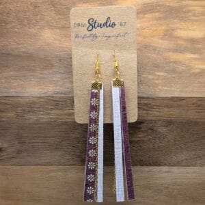 Rectangle scrapbook paper long, thin size earrings, with layers and felt core and mod podged finish. Front and back are coordinated colors, one side maroon and offwhite daisys, the other side is a textured white/purple. Gold chain dangles and gold colored metal accents. Front and back are shown