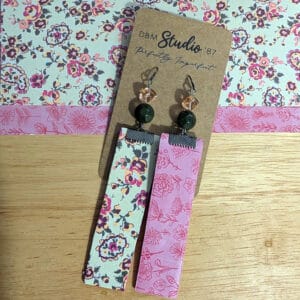 Pink, purple and green floral earrings with pink floral backs. Green and pink beads with pewter tone. Front and back are shown. Earrings are displayed on wooden table with corresponding scrapbook paper behind them.