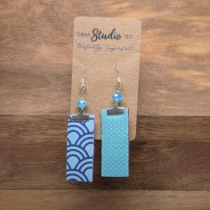 Medium length scrapbook earrings rectangles with purple felt core. Front is Light blue with purple swirls. Back is Light blue polka dots. Light blue/peal beads and pewter-toned metals. Back and front are shown