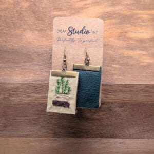 Rectangle hand embroidered fabric medium size earrings with felt core and pleather back. Front is a hand embroidered potted plant on a shelf, back is a forest green pleather. Coupled with a bronze colored metal finishes. Front and back are shown