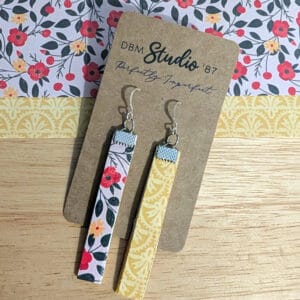 Slim, lightweight mismatched dangle earrings featuring a soft floral pattern with red and yellow blossoms on one side and a warm mustard-yellow design on the other, finished with silver-tone hooks.