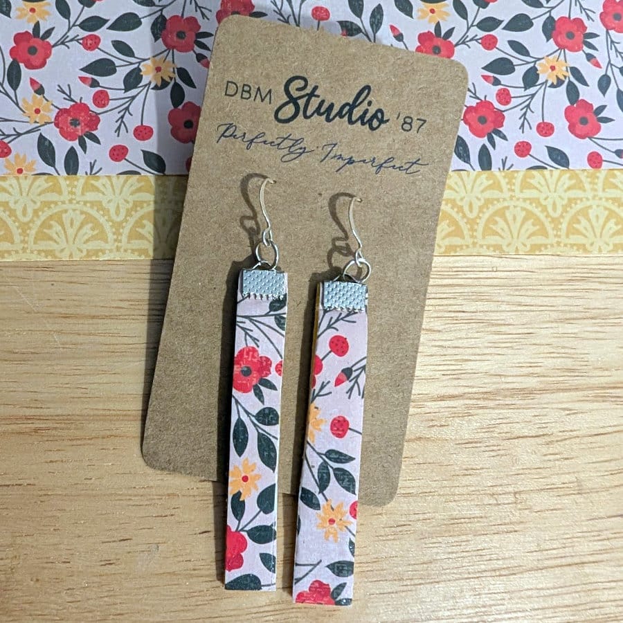Slim, lightweight dangle earrings featuring a soft floral pattern with red and yellow blossoms on the front finished with silver-tone hooks.